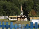 Image of a traditional wooden church behind locked wooden gate near Coñaripe, Chile.
