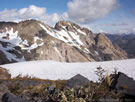 A view of a steep, rocky mountain in the background with a snowfield, Radal Siete Tasas National Park.