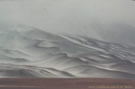 An image of slopes covered by snow which dissolve in the white, foggy sky.