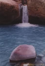 An image of a small waterfall with a stone in the foreground, in the Yerba Loca valley, Chile.
