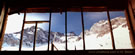An image of a wooden window frame through which a glacier of El Morado can be seen, taken from the road to Embalse de Yeso in the military barracks.